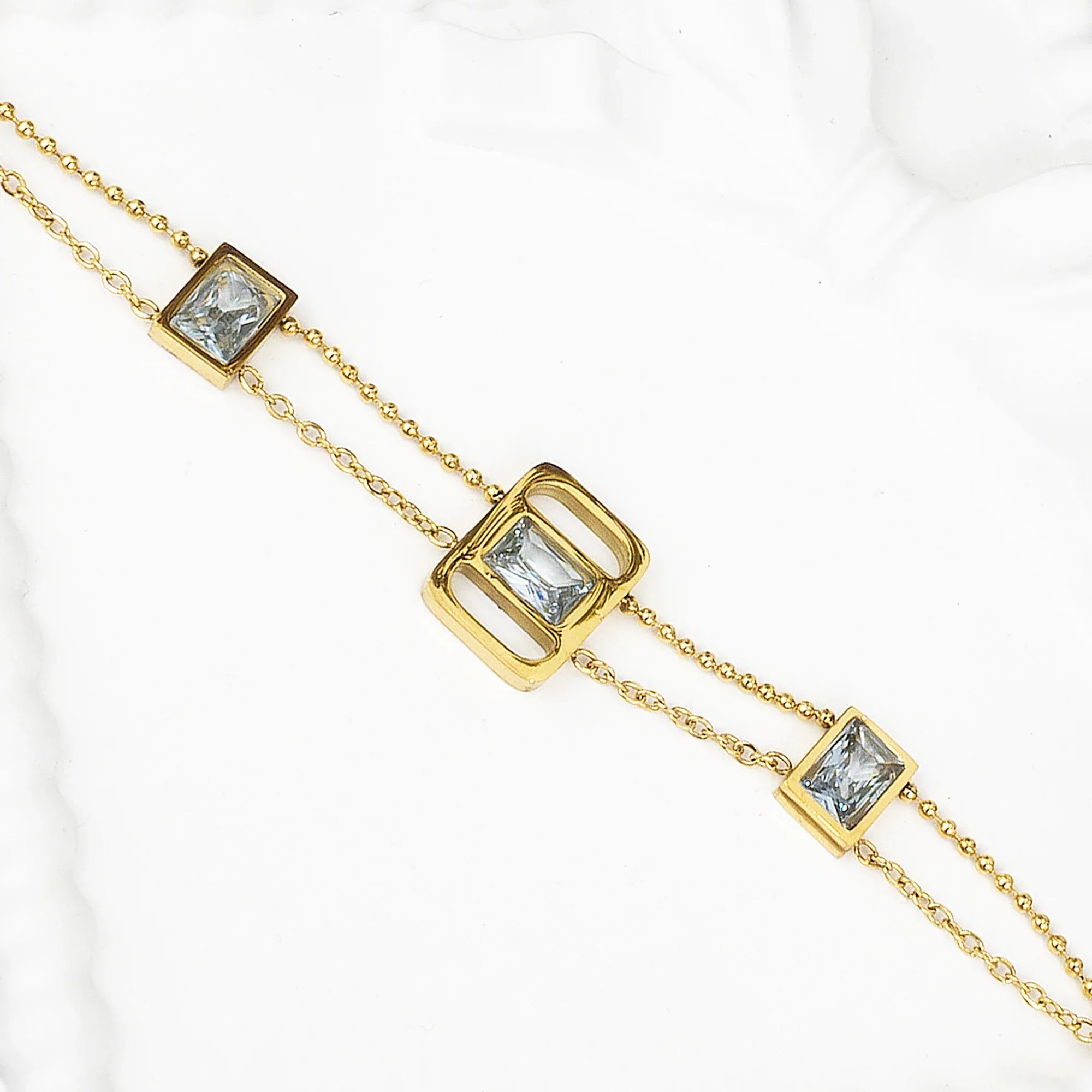 Gold necklace with square gemstones on a white background