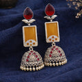 Ornate earrings with red and yellow stones on a blue fabric background