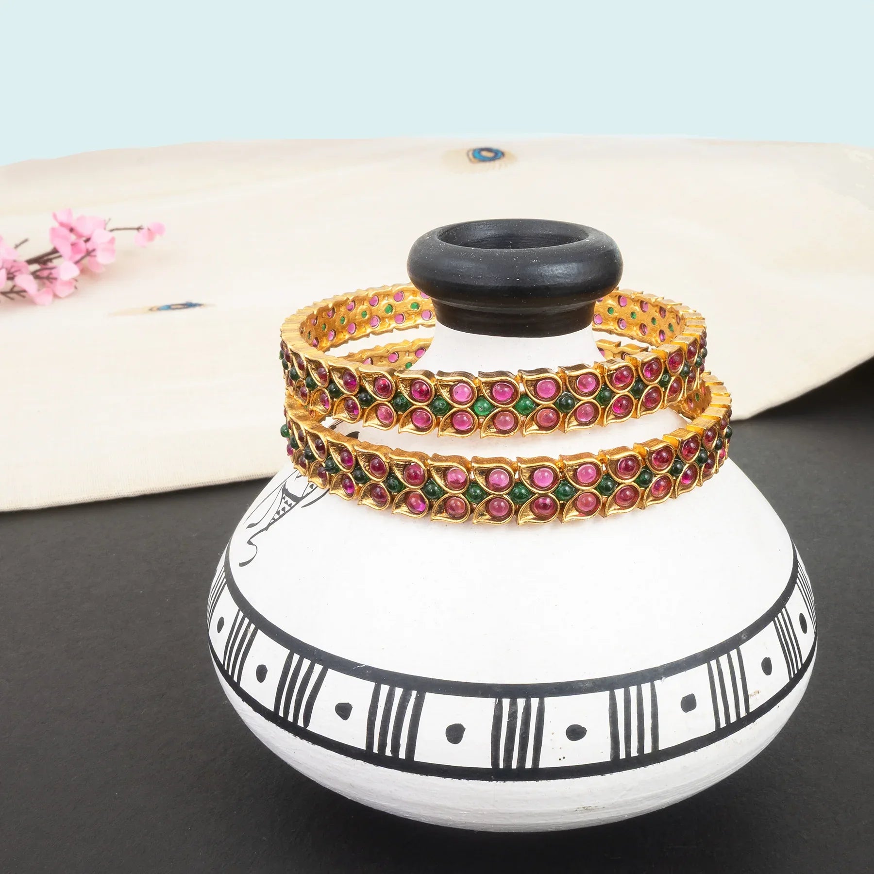 Decorative pot with colorful bangles on a light blue background