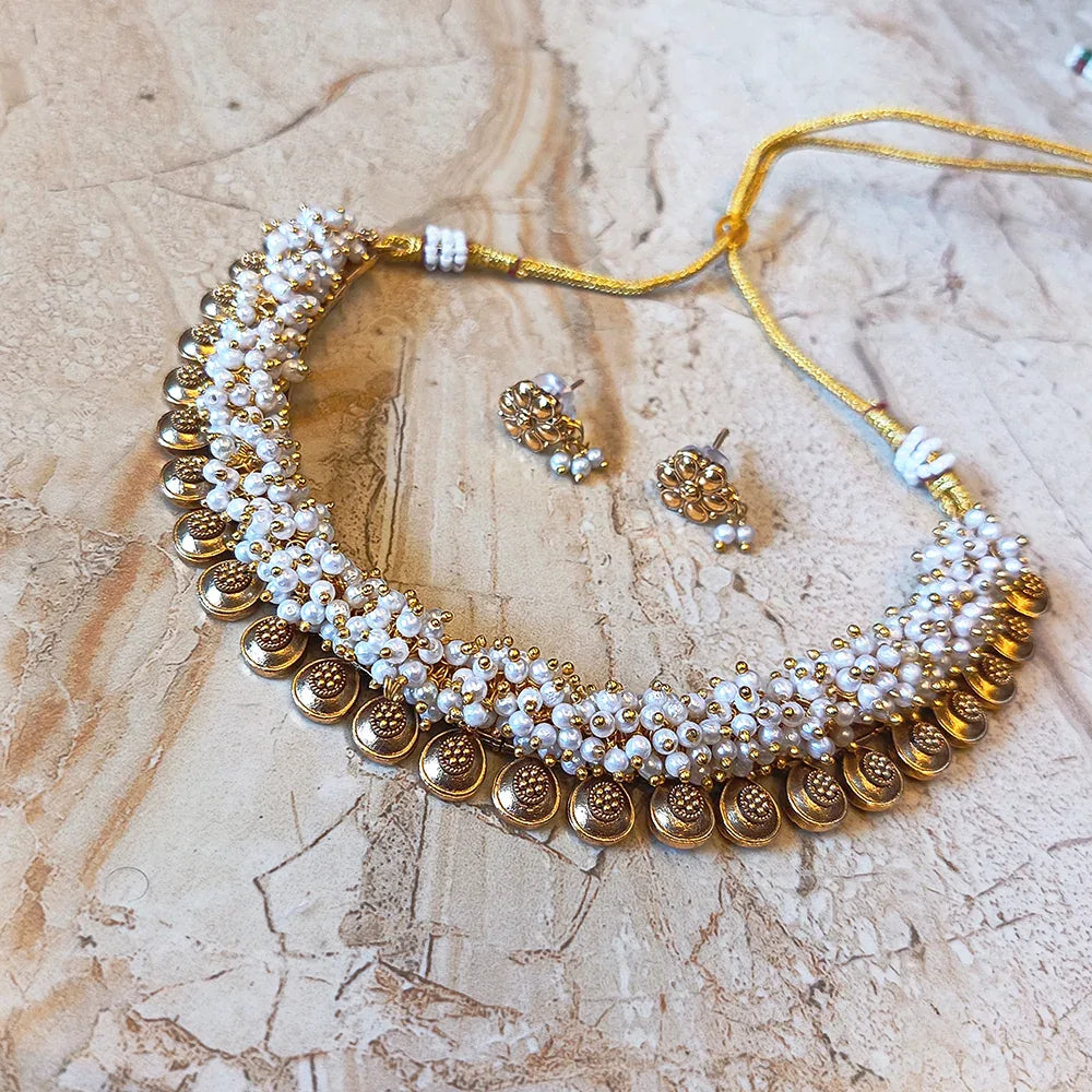 Gold and pearl necklace with matching earrings on a marble surface