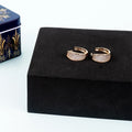 Gold hoop earrings on a black jewelry box with a decorative box in the background
