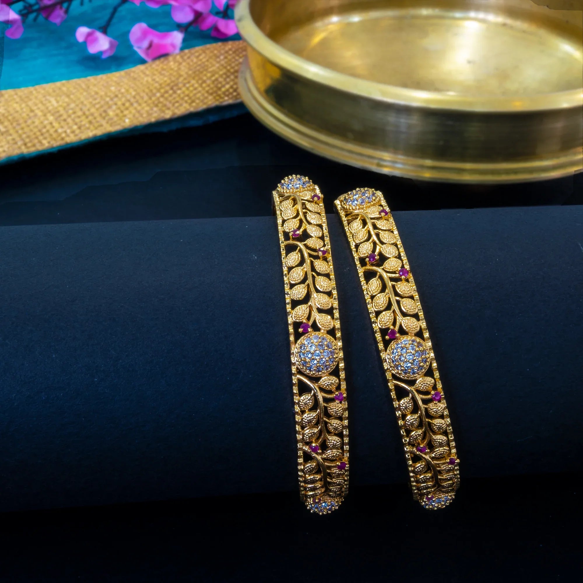 Gold earrings with intricate designs on a dark surface