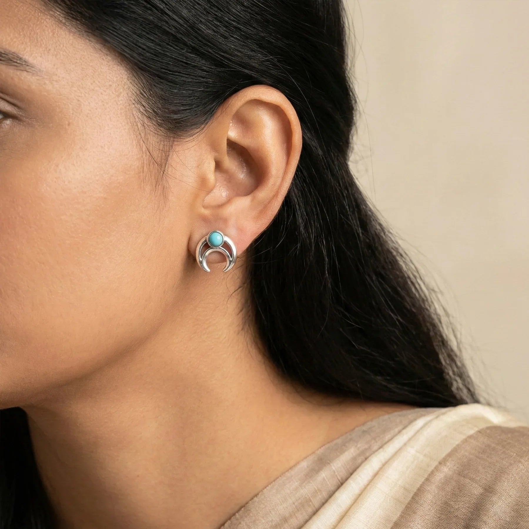 Close-up of a woman wearing a silver earring with a turquoise stone.