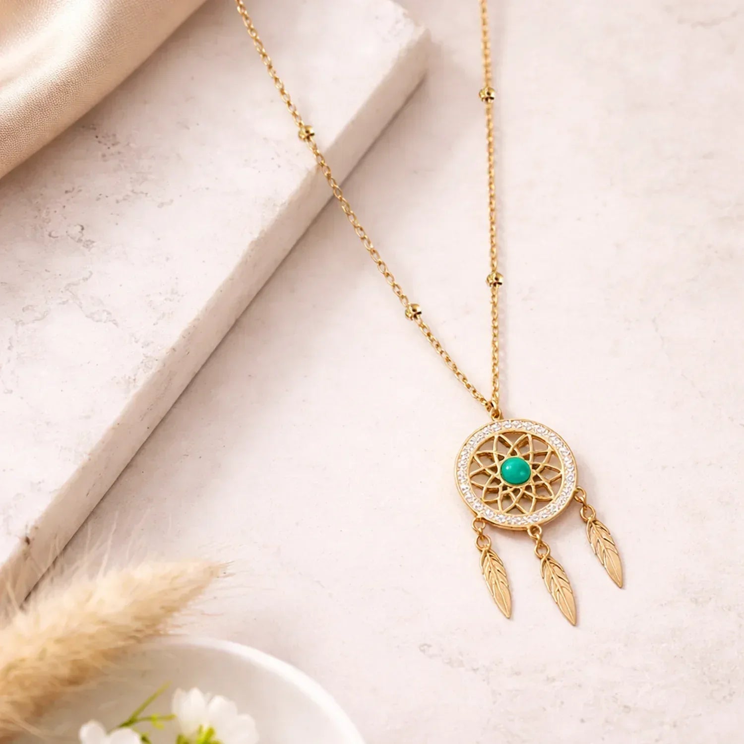 Gold necklace with a dreamcatcher pendant on a light surface