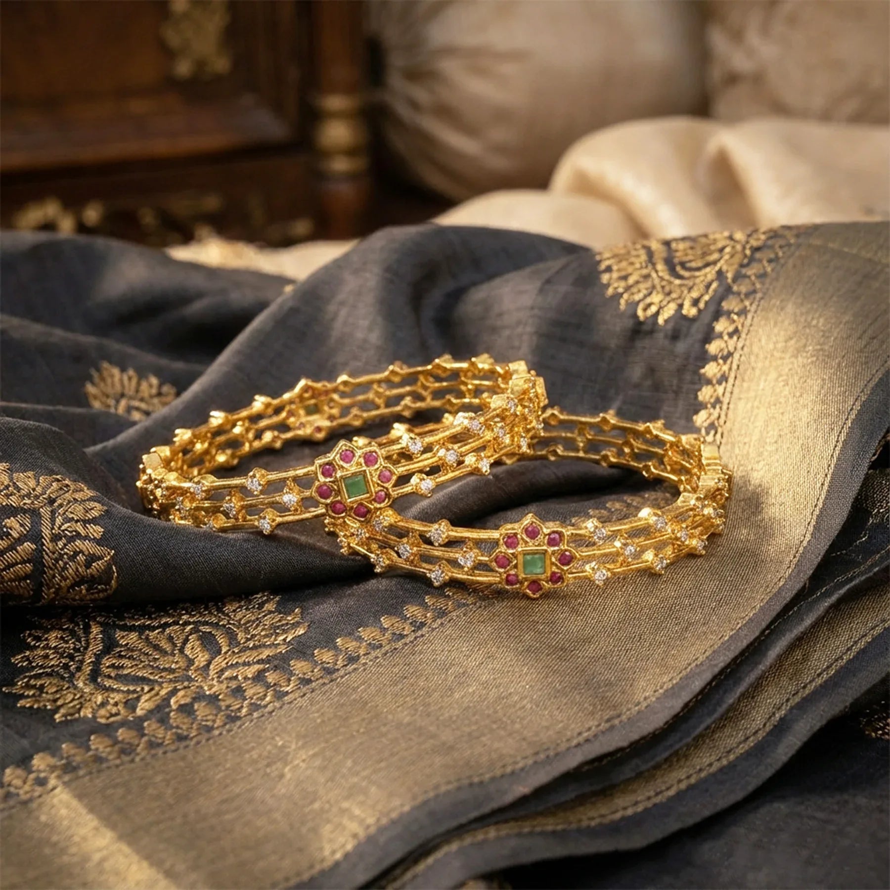 Gold bracelets with gemstones on a dark fabric background