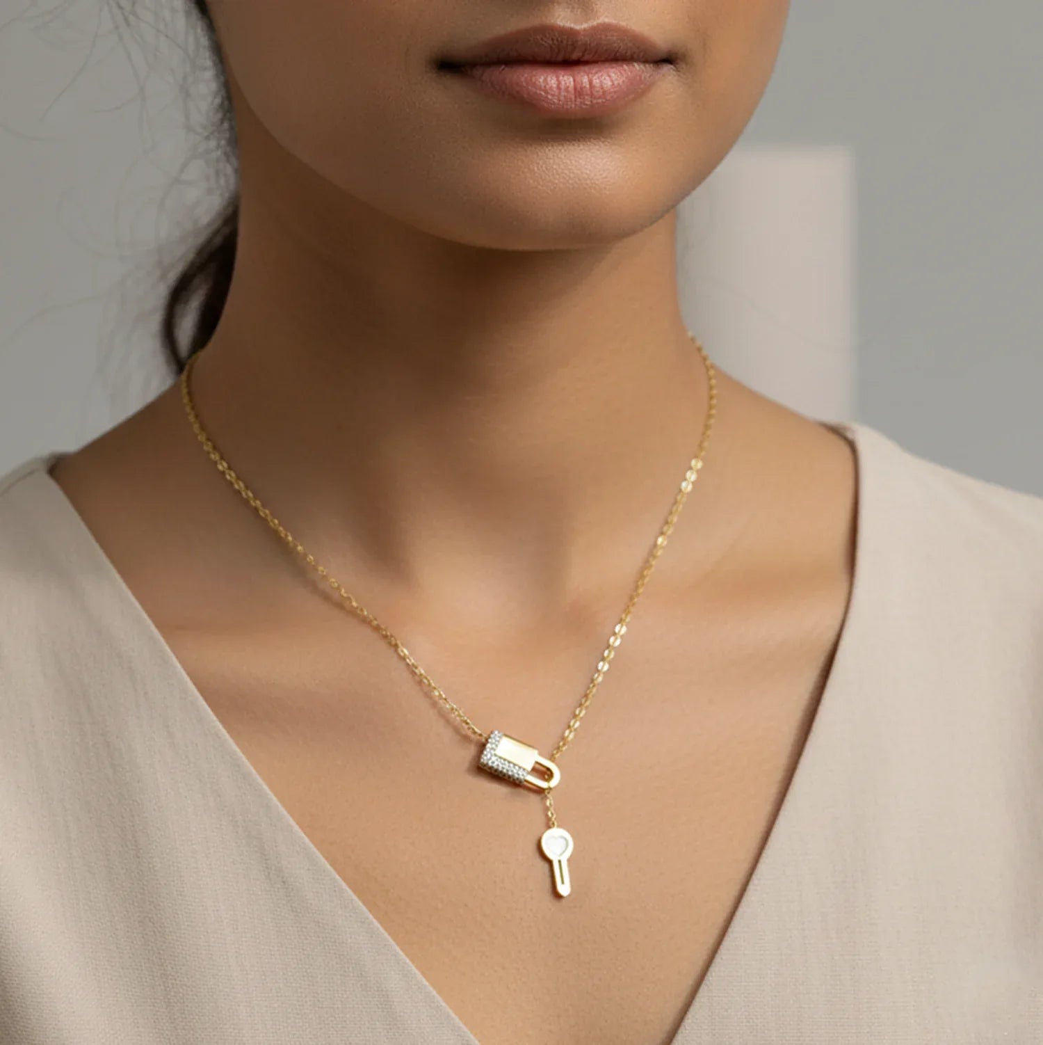 Gold necklace with a lock and key pendant on a neutral background