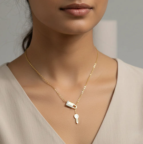 Gold necklace with a lock and key pendant on a neutral background