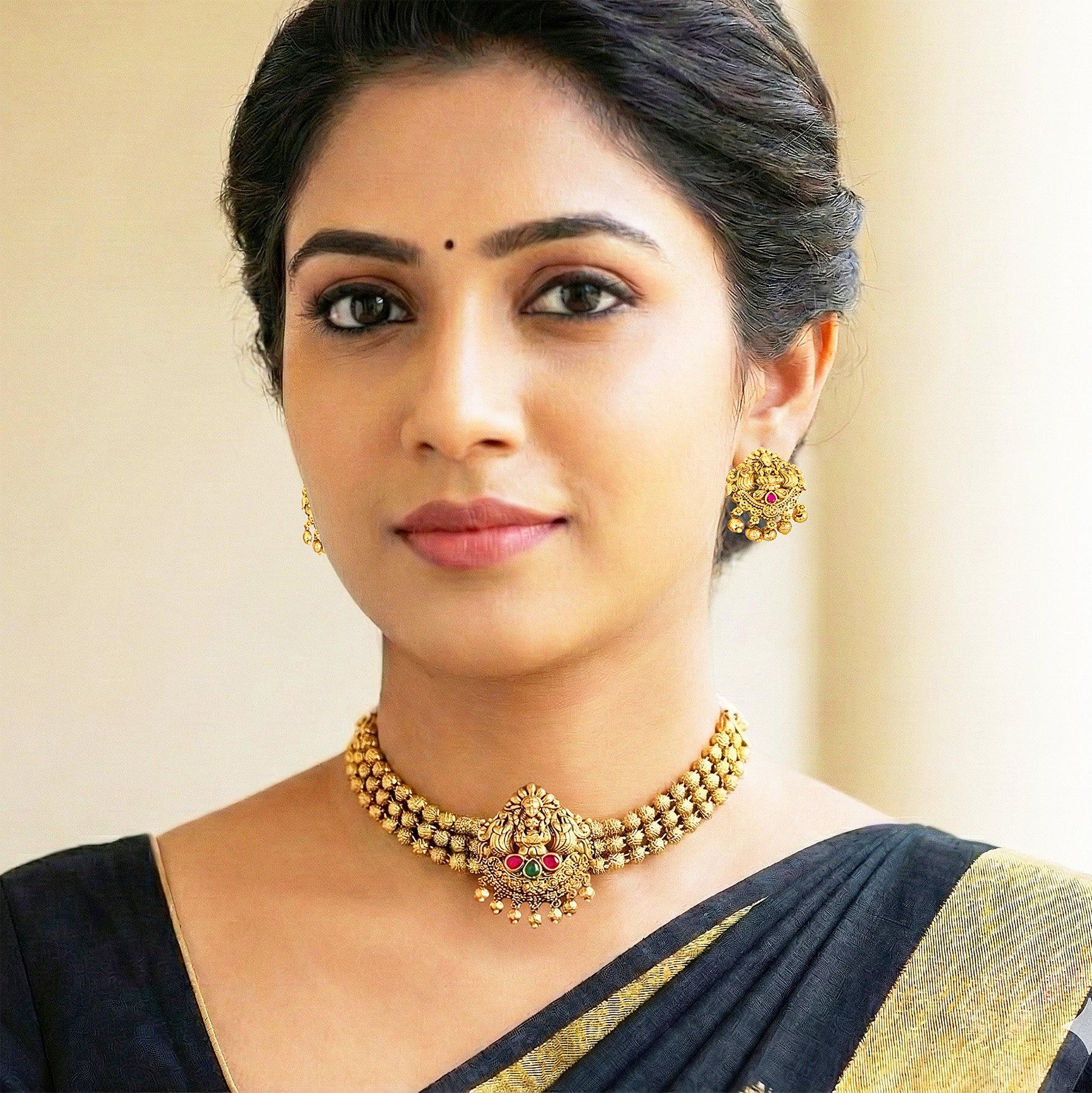 Woman wearing gold jewelry against a beige background