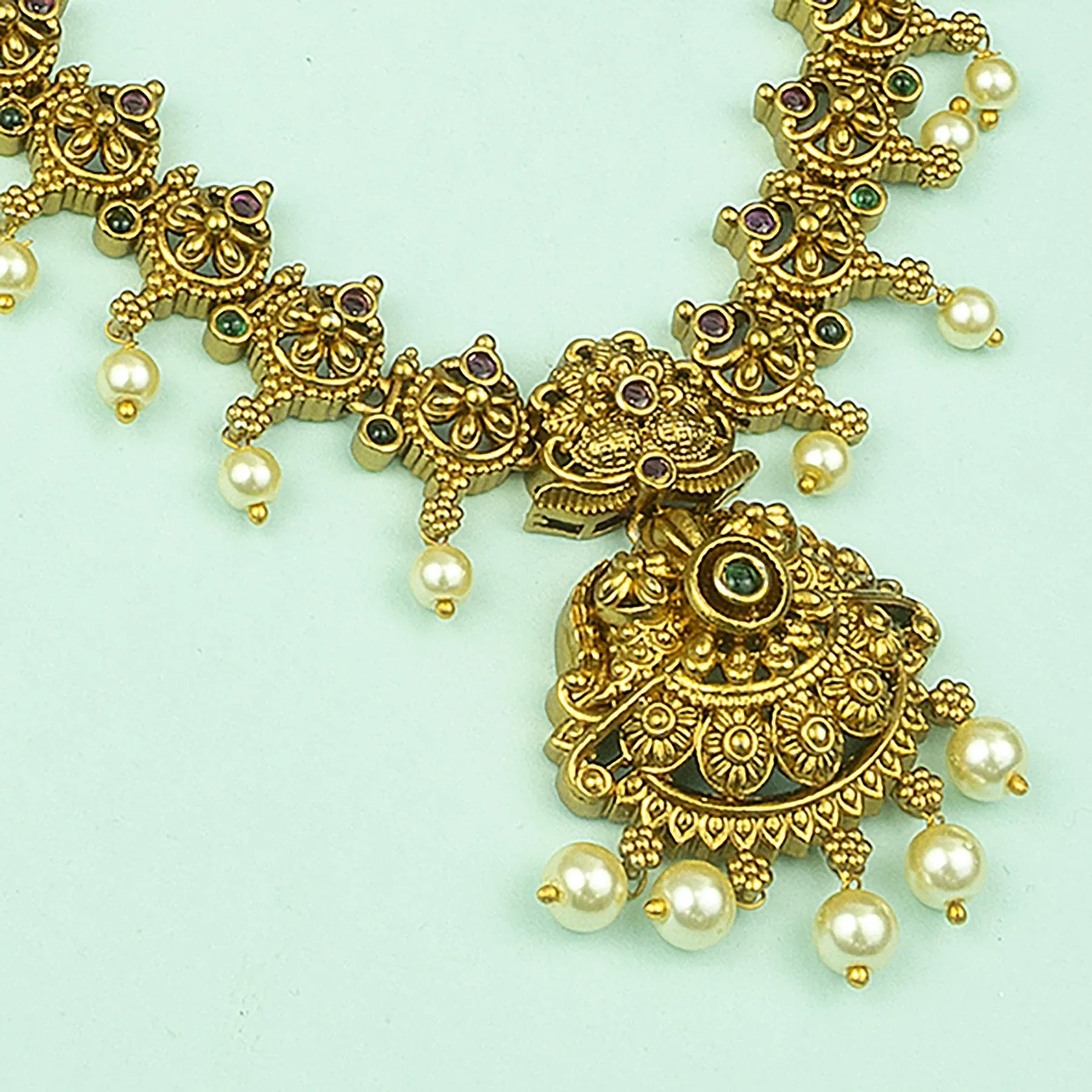 Gold necklace with pearls on a light green background