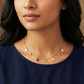 Woman wearing a gold necklace with star-shaped pendants on a neutral background