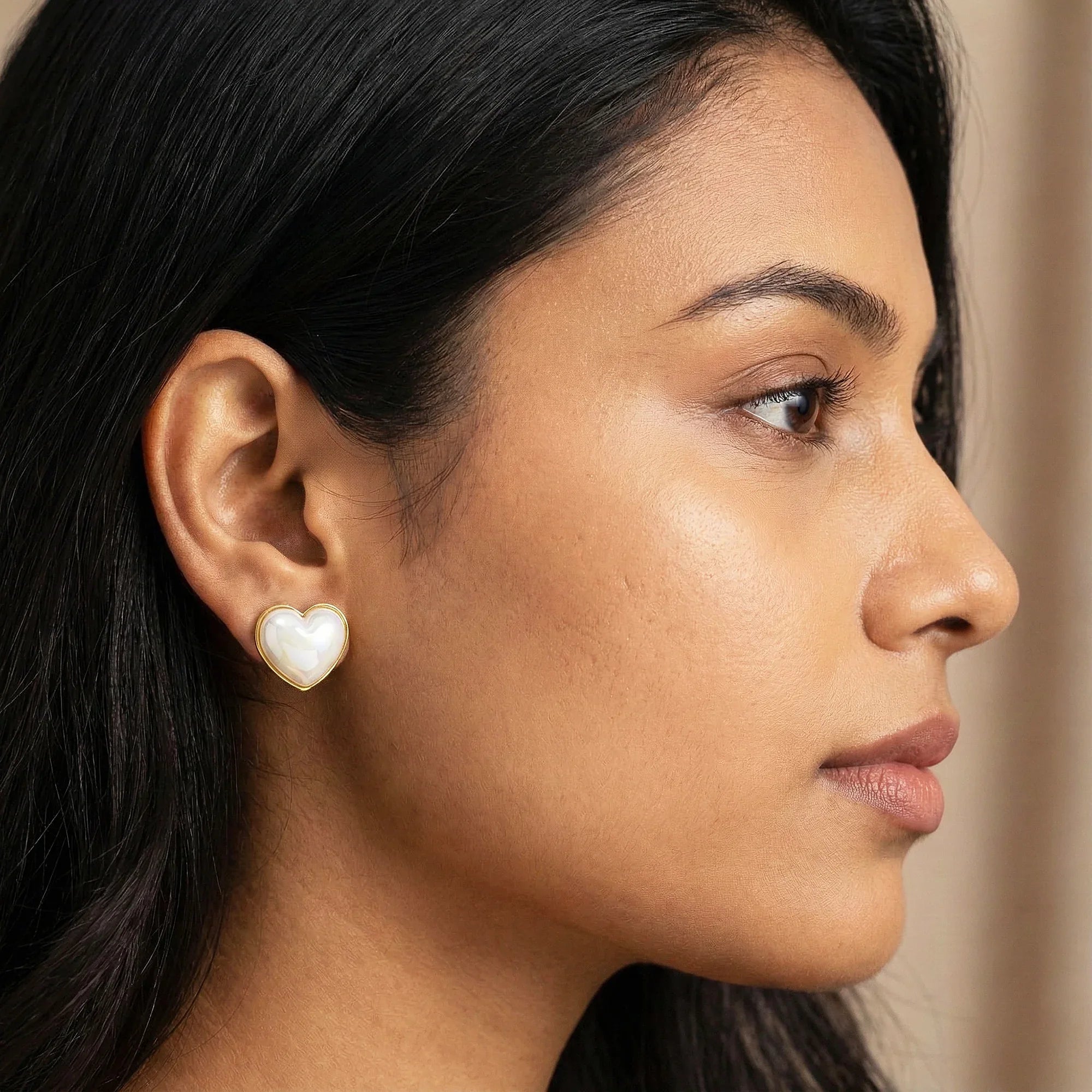 Close-up of a woman wearing a heart-shaped pearl earring.