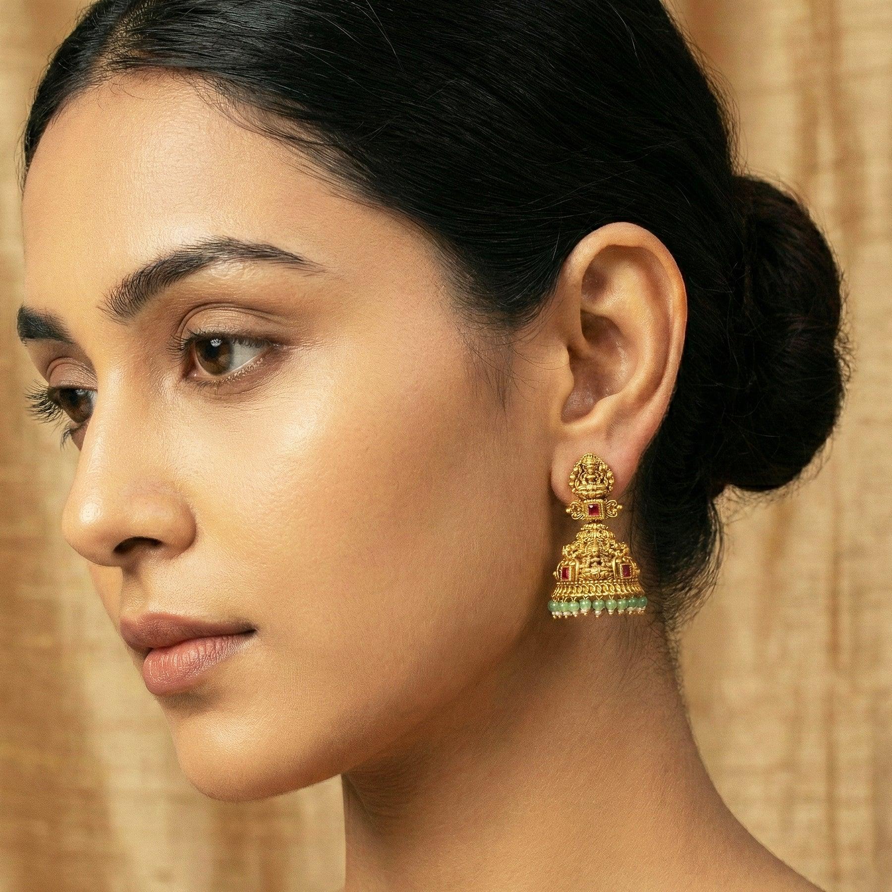 Close-up of a woman wearing gold earrings with a neutral background