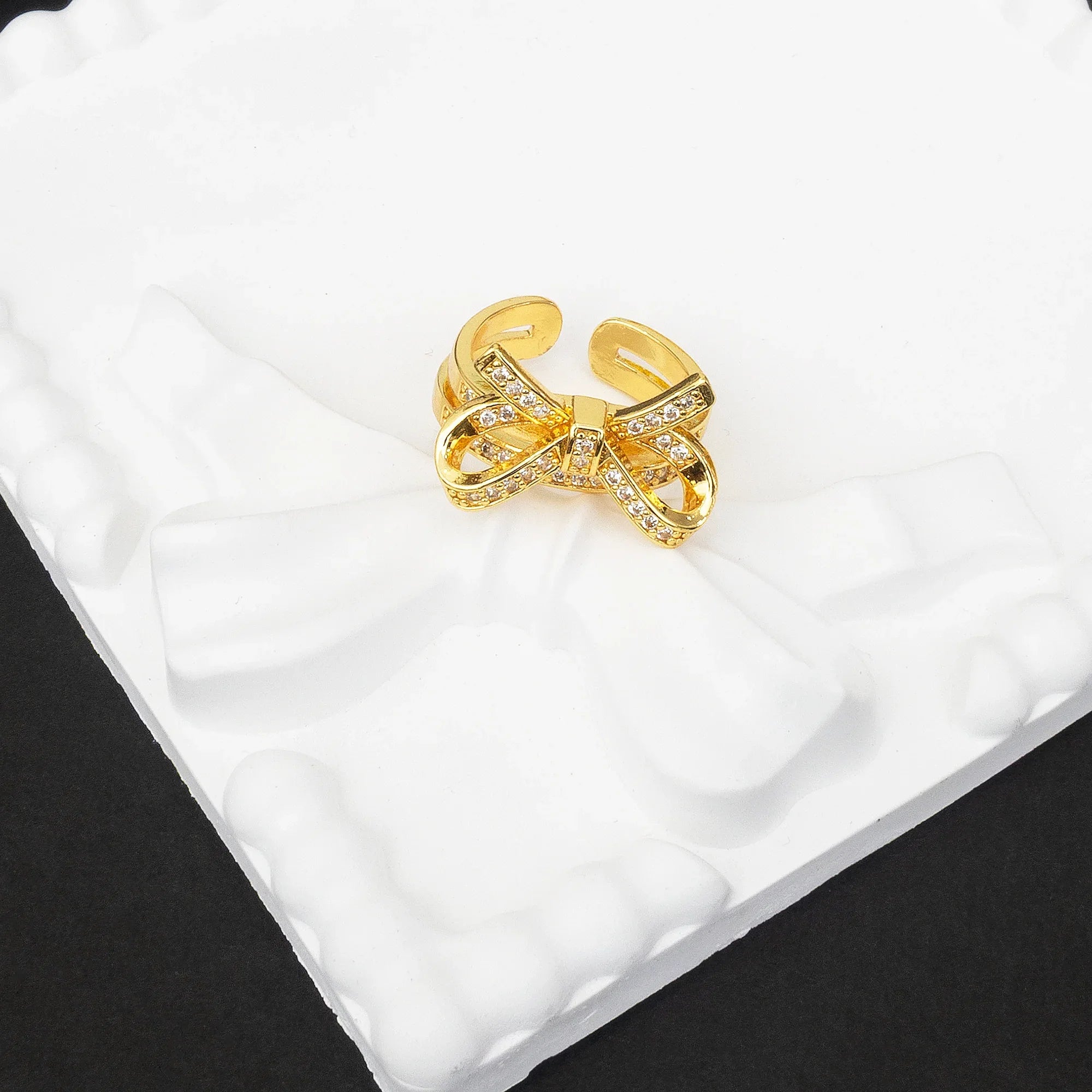 Gold bow-shaped ring on a white cushion