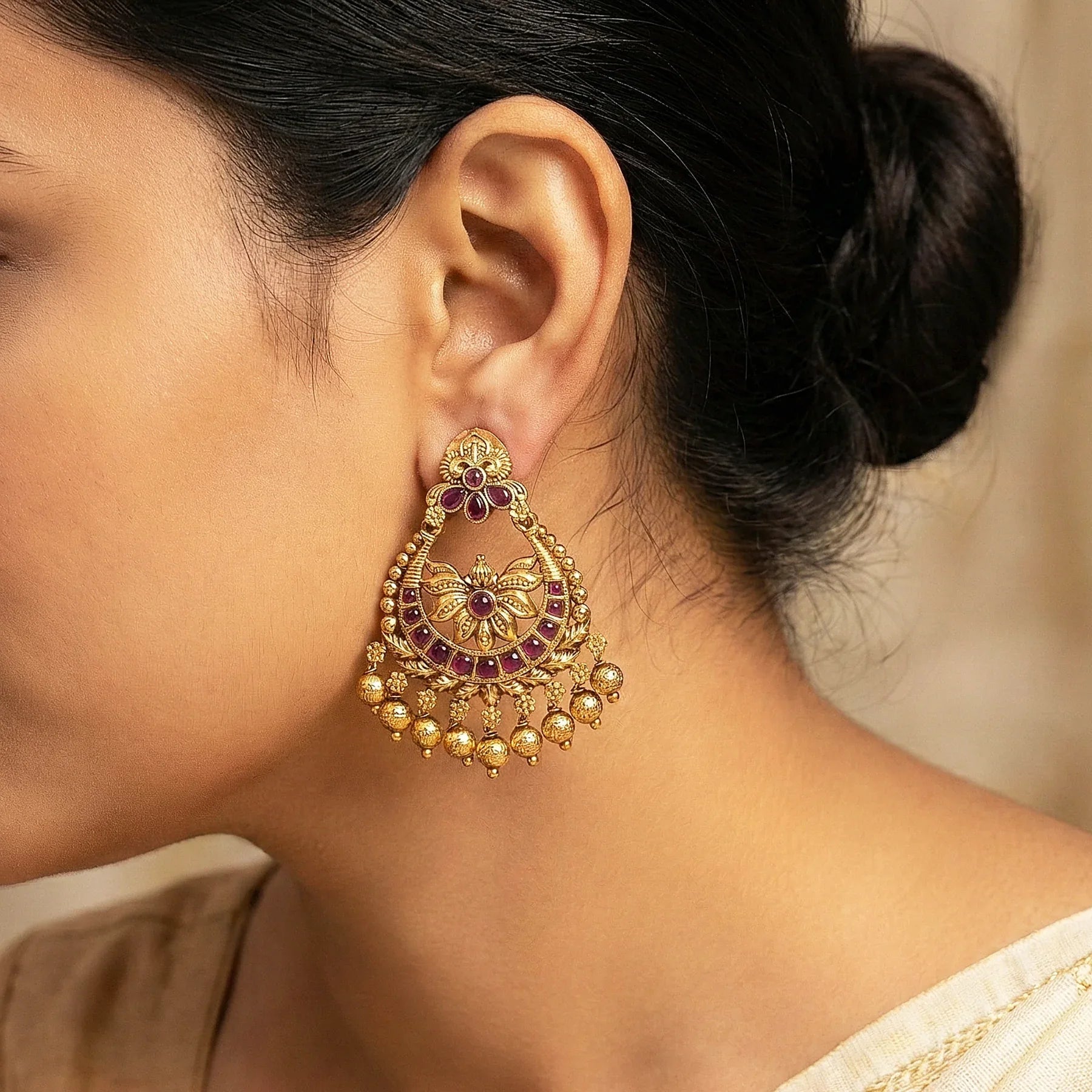 Close-up of a person wearing a gold and red gemstone earring.