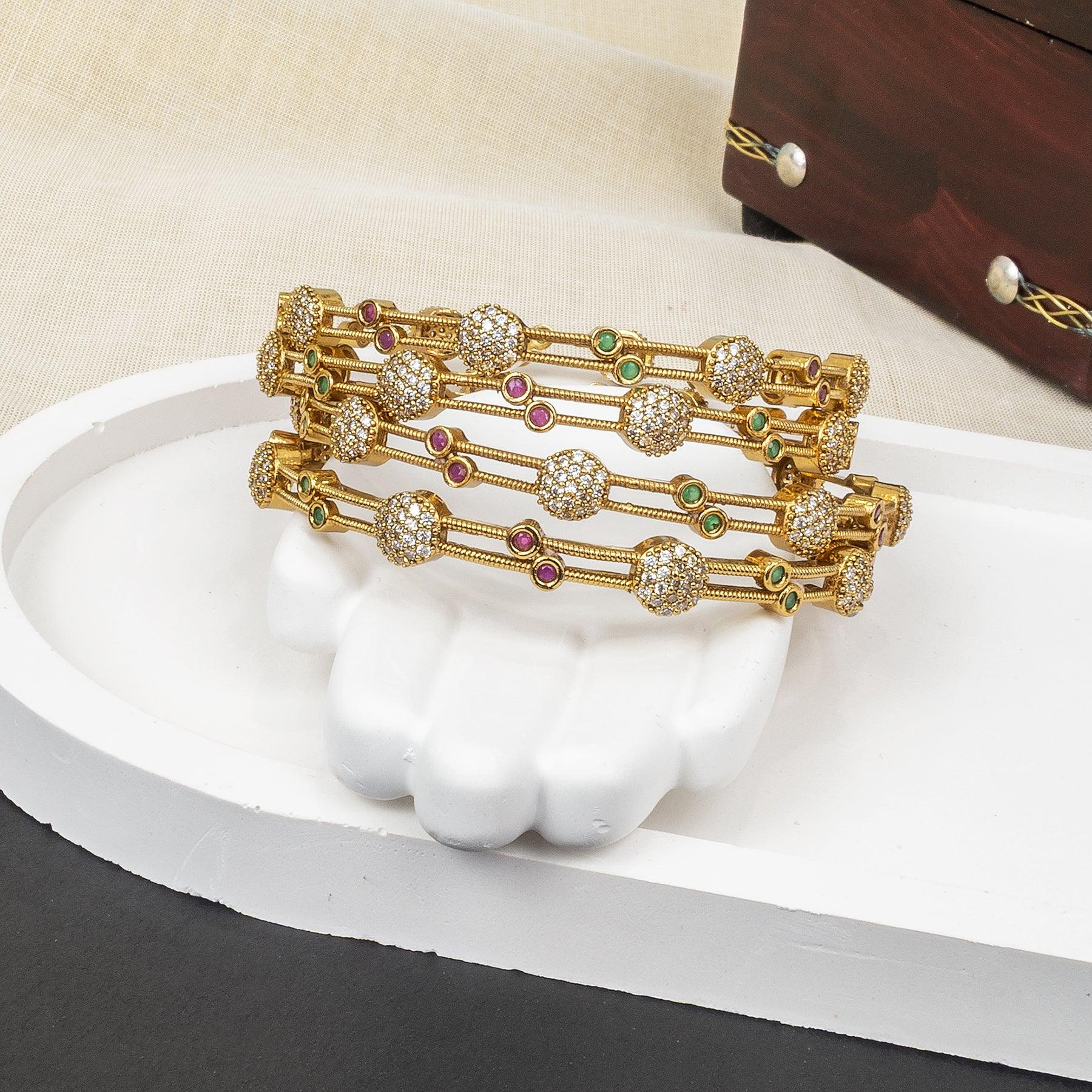 Set of gold bracelets with gemstones on a white stand