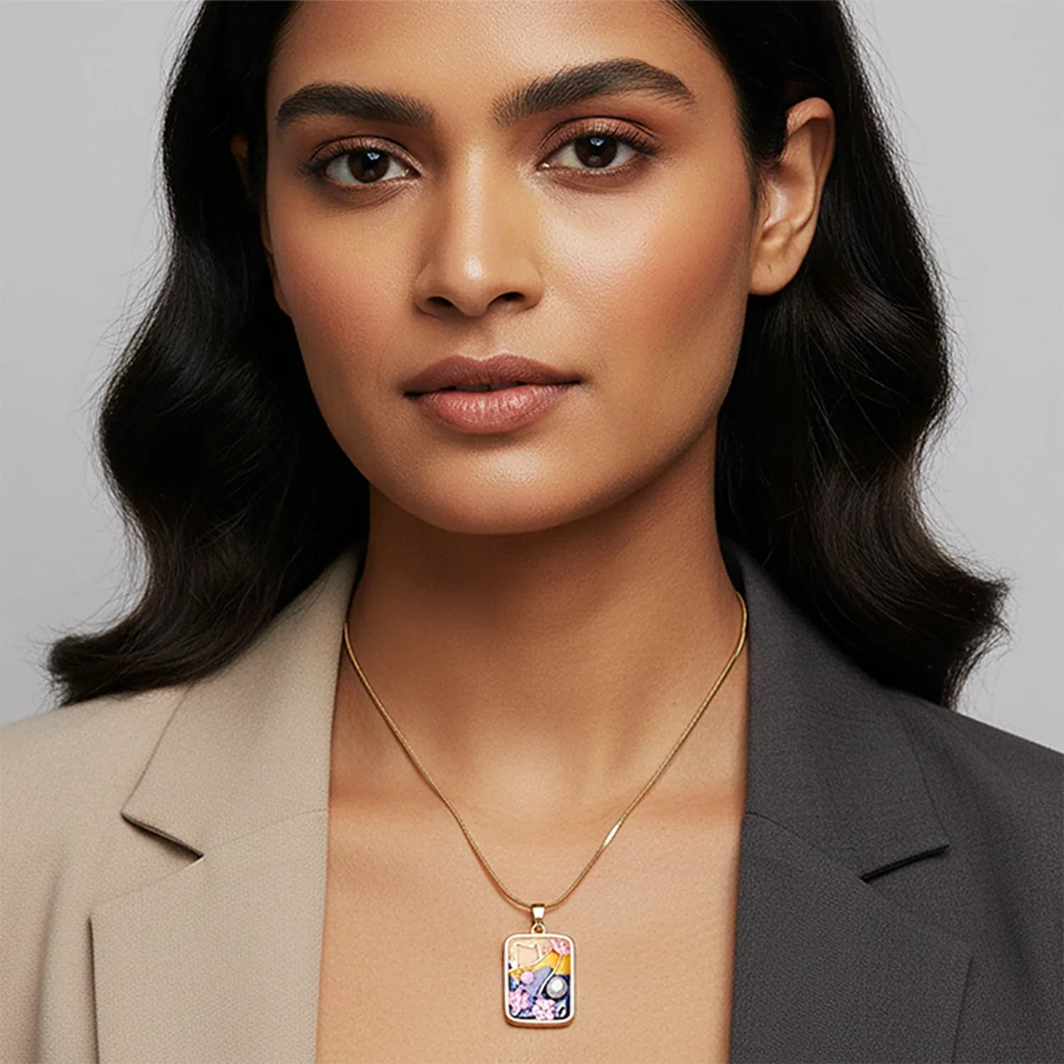 Woman wearing a gold necklace with a colorful pendant against a gray background