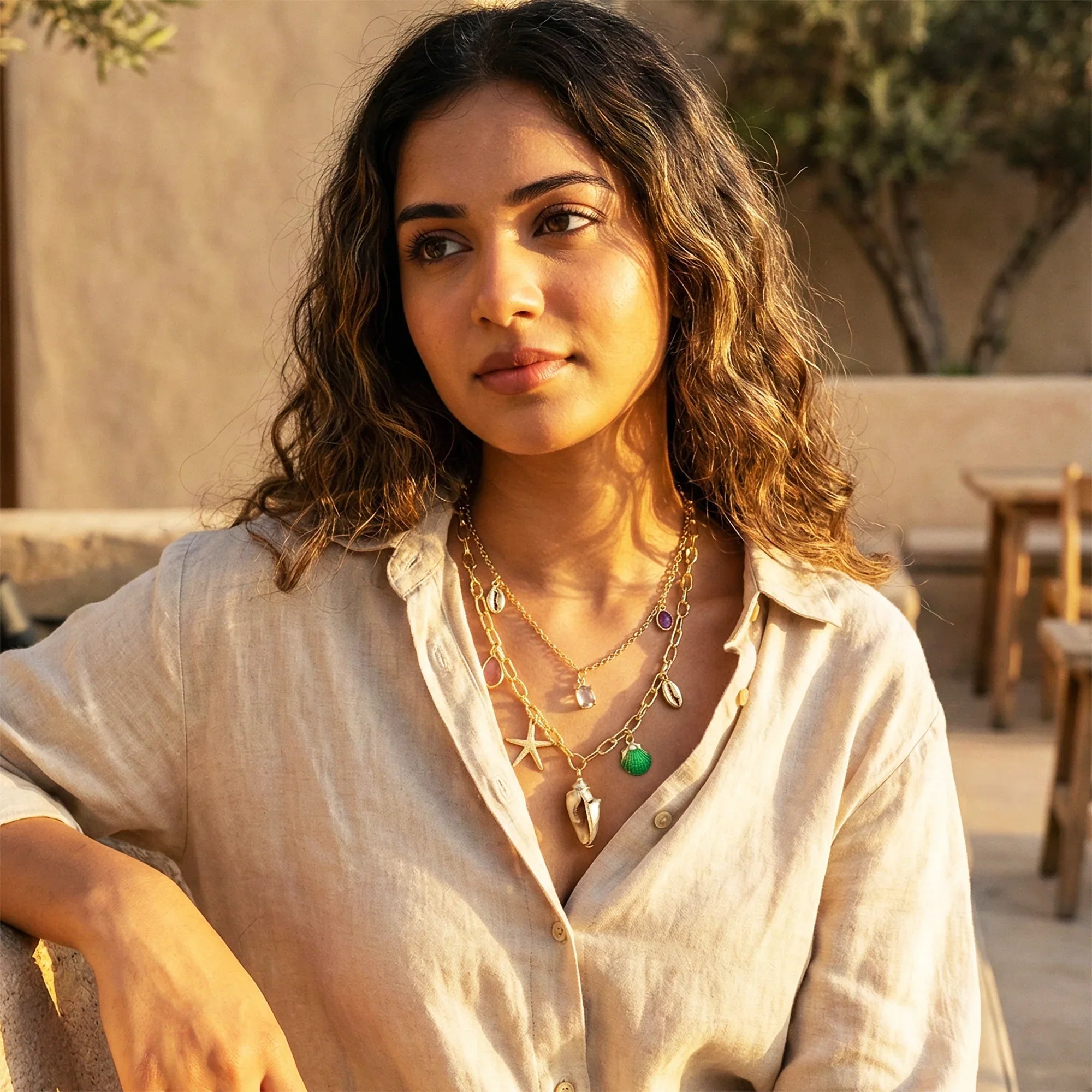 Woman wearing layered necklaces outdoors with a warm glow