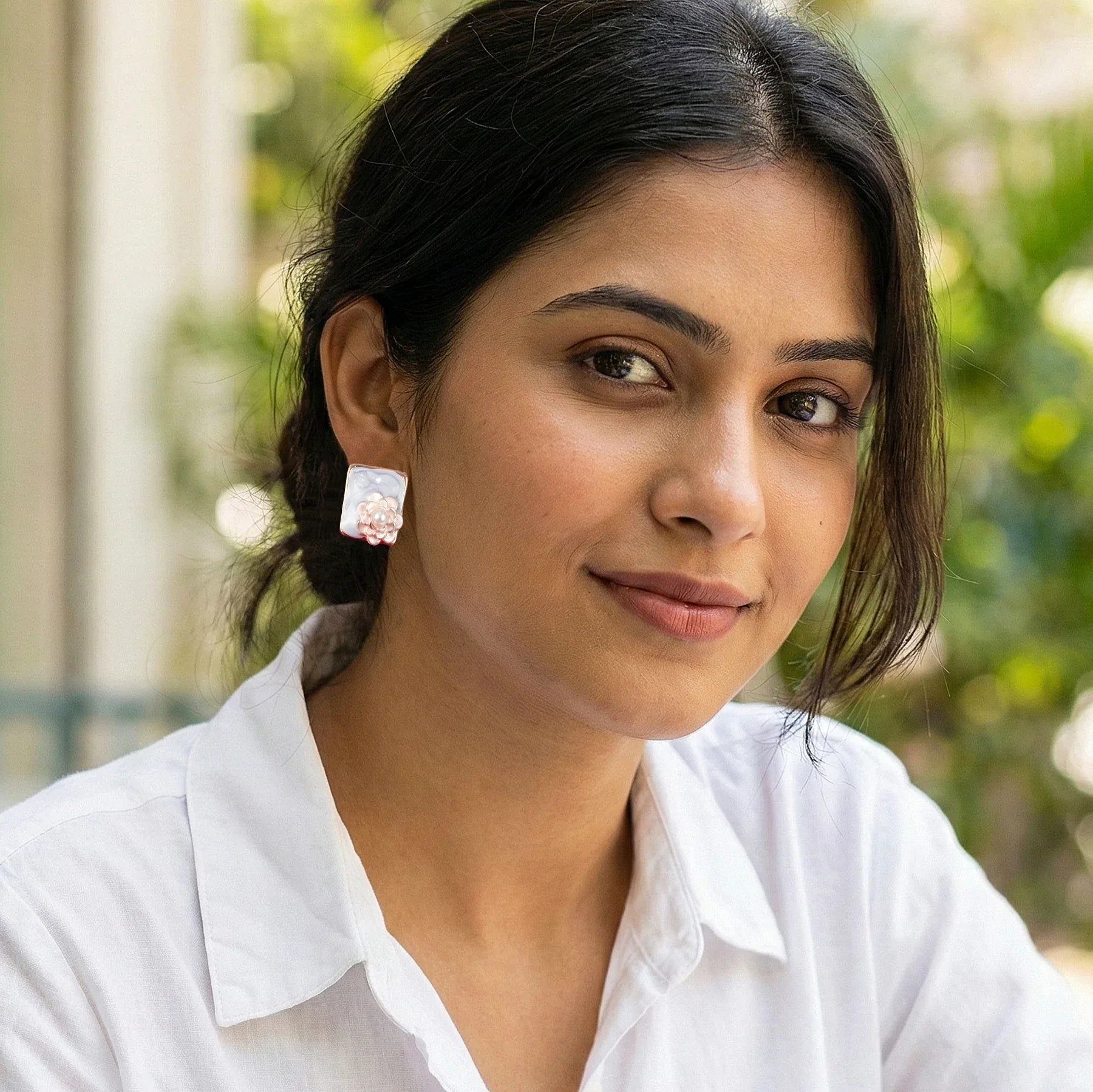 Woman wearing a white shirt with a blurred green outdoor background