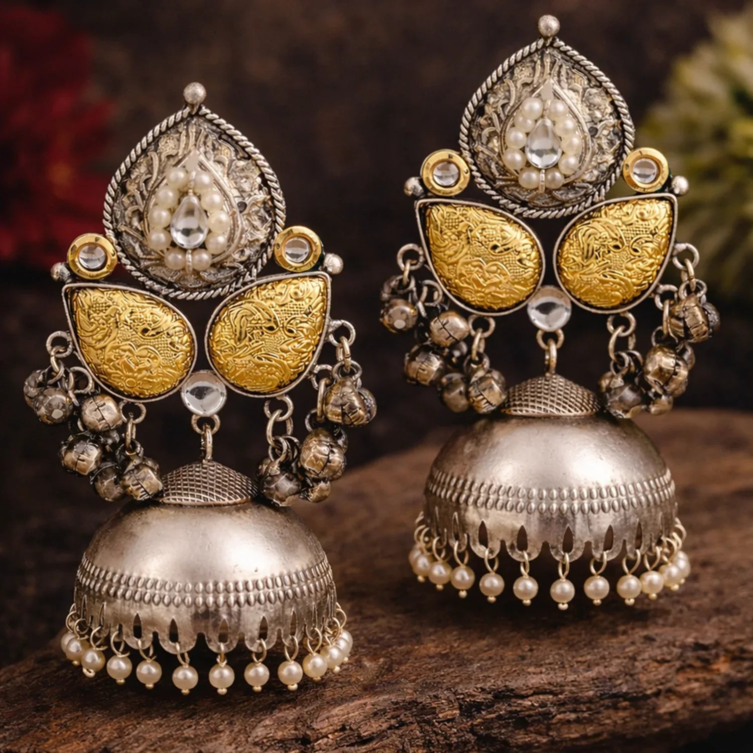 Ornate silver and gold earrings with intricate designs on a wooden surface.