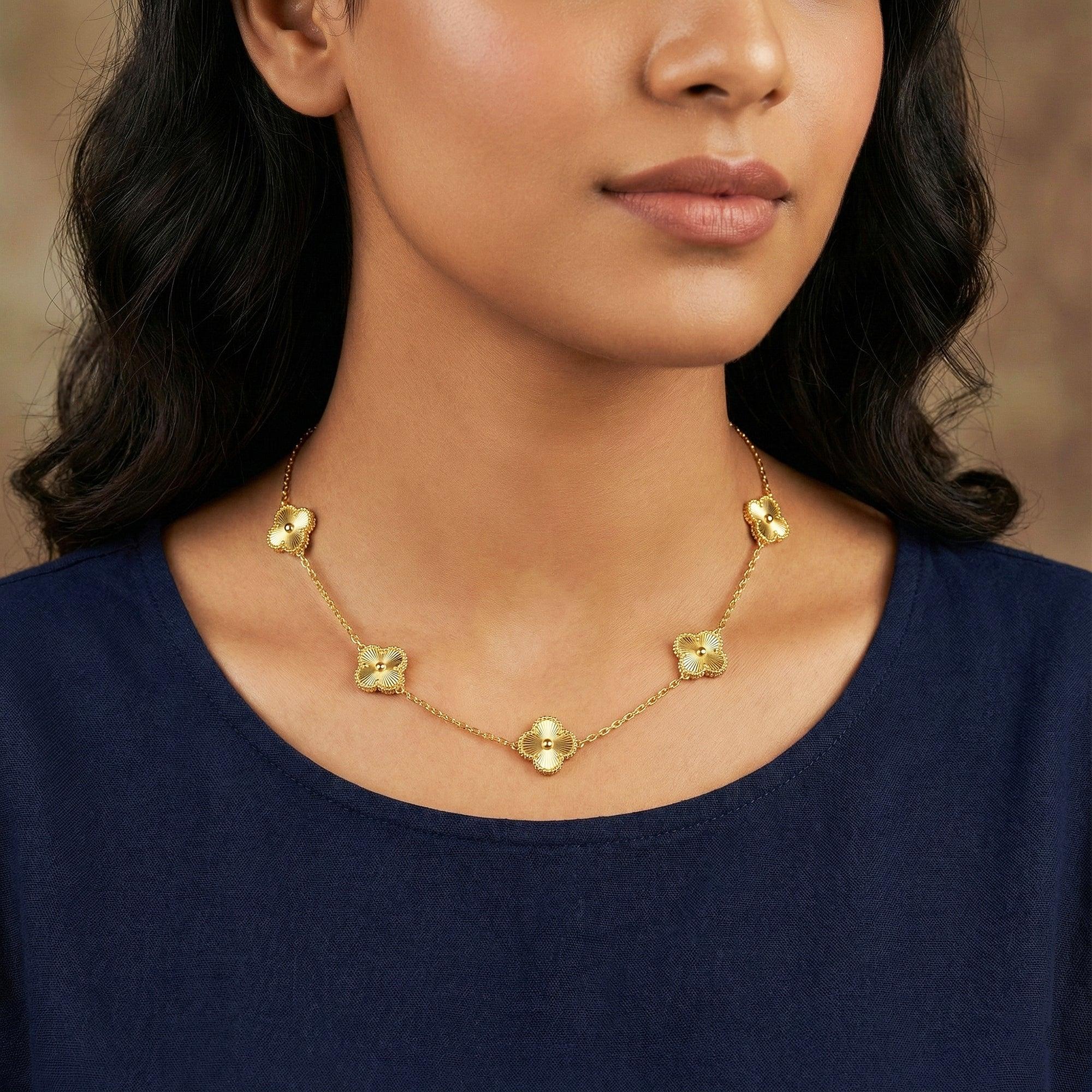 Woman wearing a gold necklace with floral pendants against a neutral background