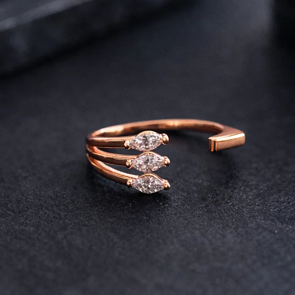 Rose gold ring with three diamond-like stones on a dark background