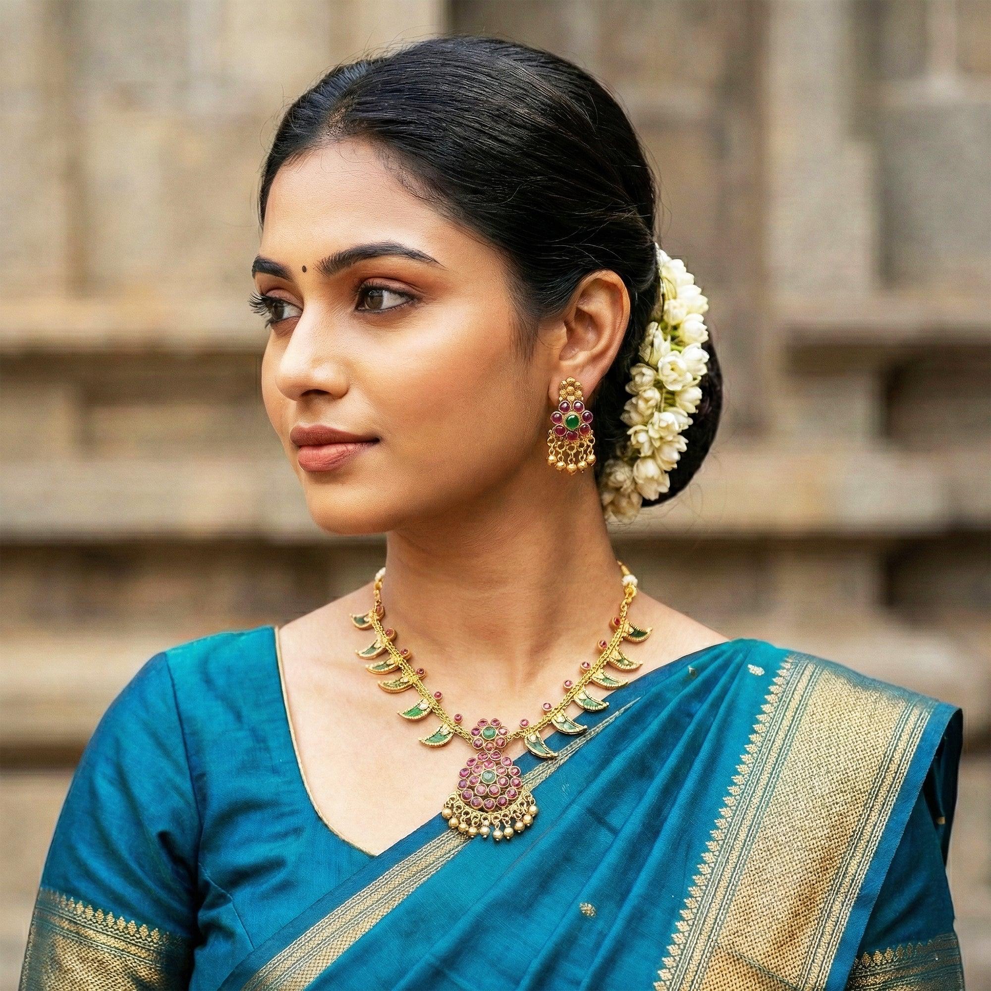 Woman in a blue saree with gold jewelry and floral hair accessories.