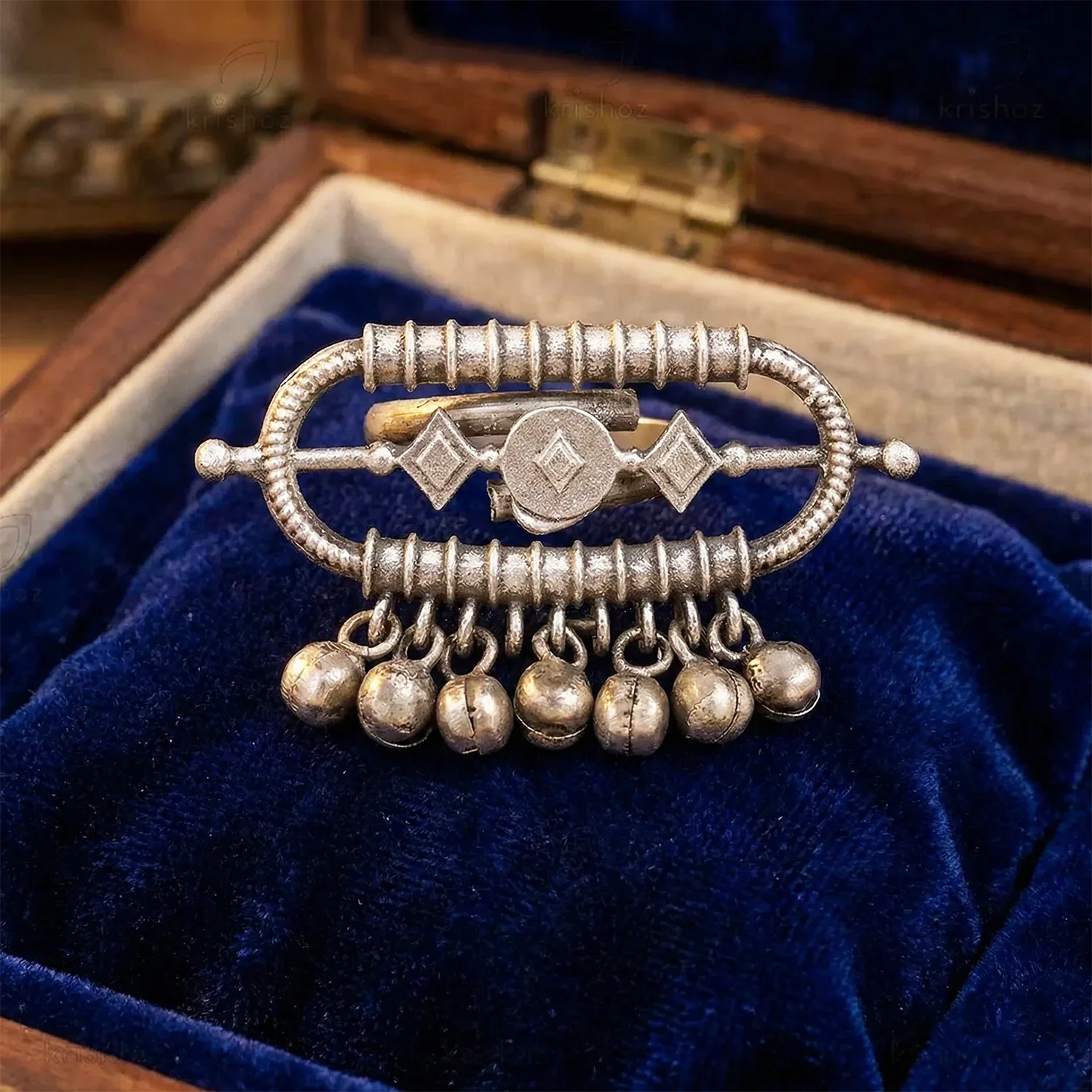 Silver brooch with hanging elements on a blue velvet background