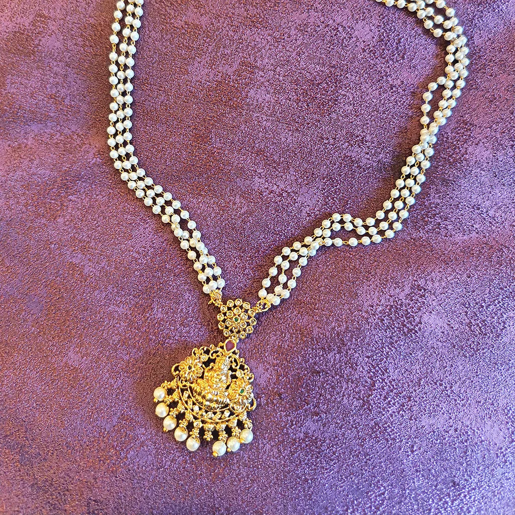 Pearl necklace with a gold pendant on a textured purple background