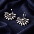 Pair of silver earrings on a dark blue fabric background