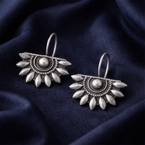 Pair of silver earrings on a dark blue fabric background