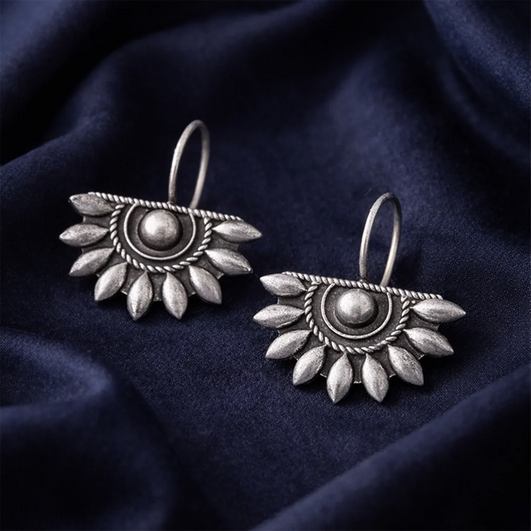Pair of silver earrings on a dark blue fabric background