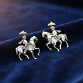 Silver earring with a design of a person on horseback on a blue fabric background
