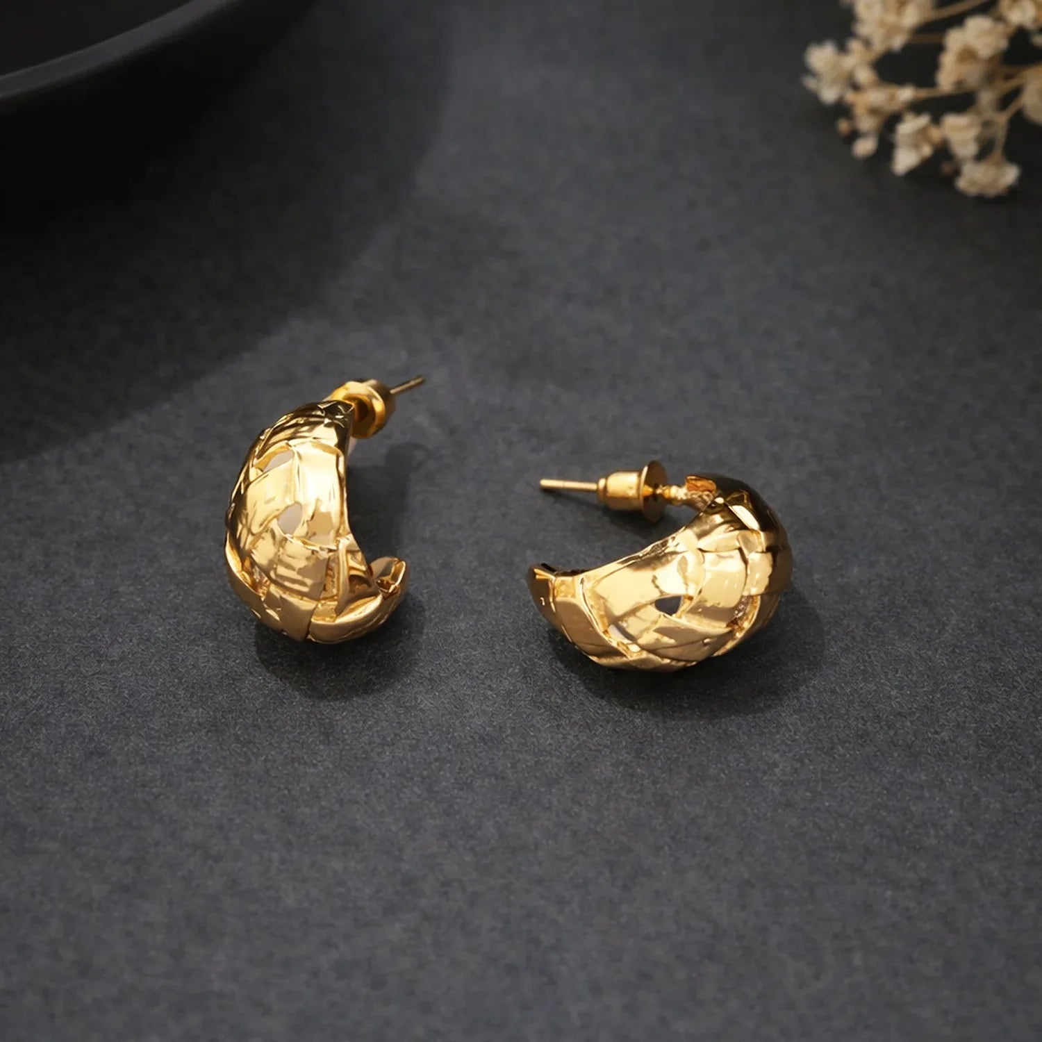Gold hoop earrings on a dark textured surface