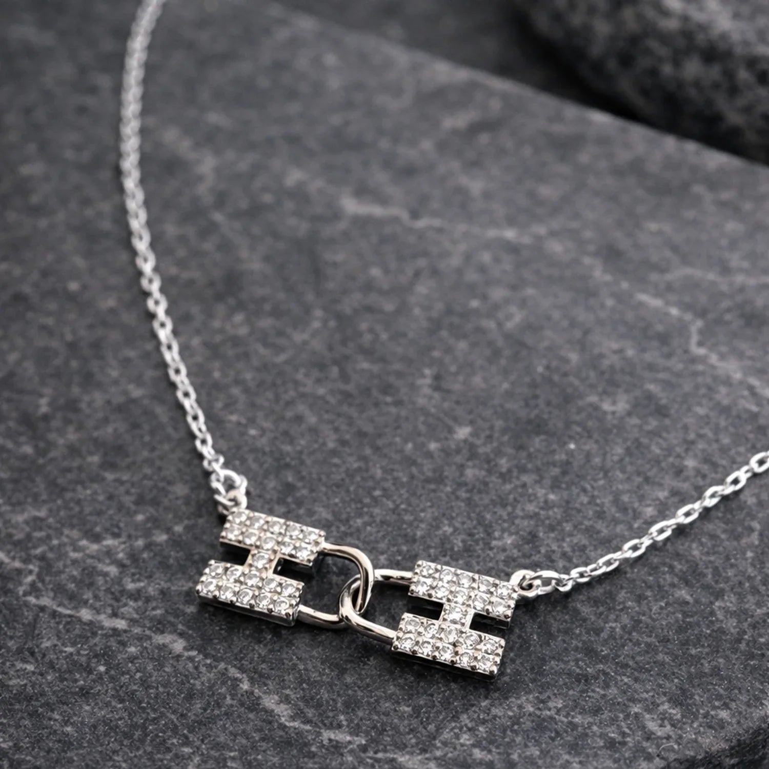 Silver necklace with a unique clasp design on a dark stone surface
