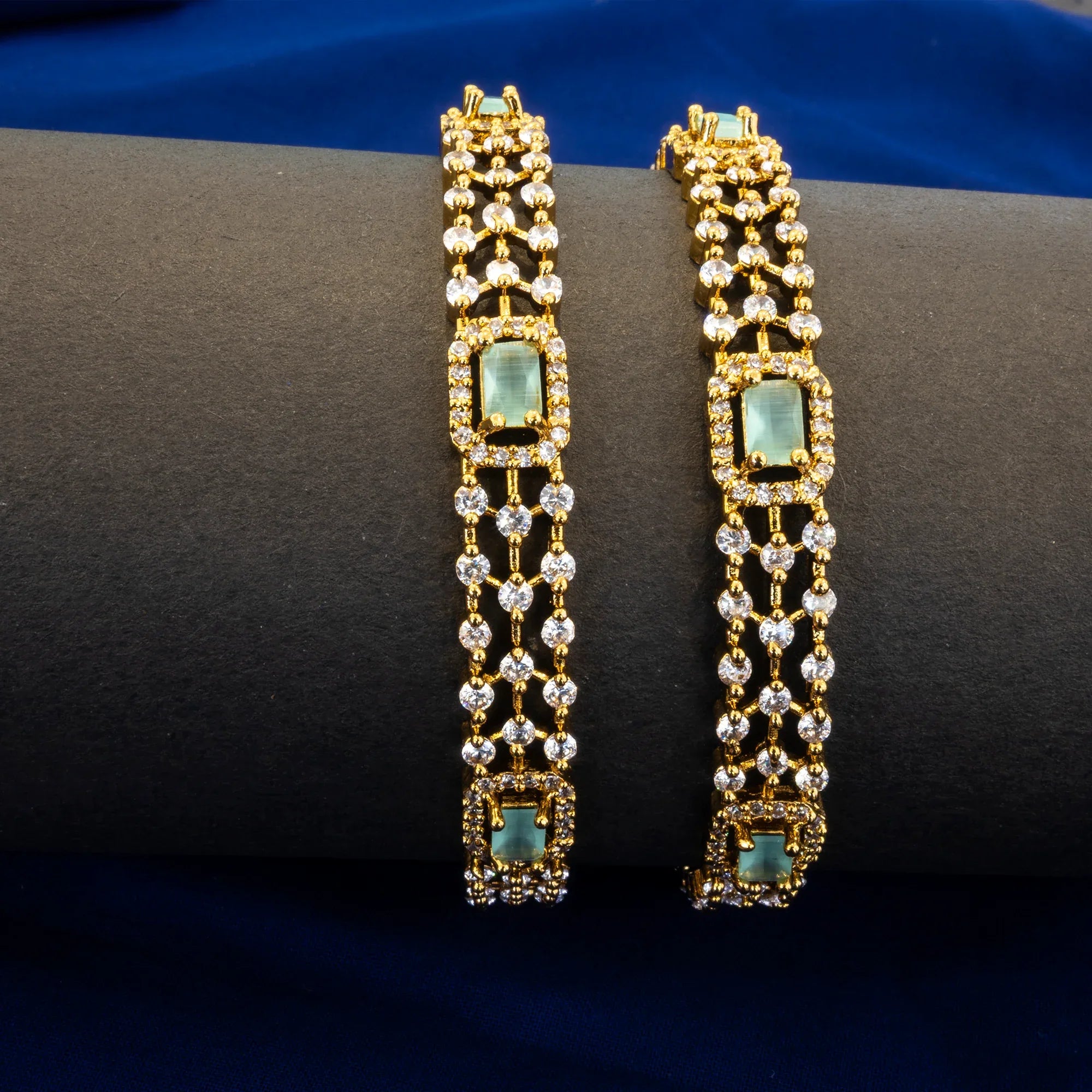 Gold and diamond bracelet on a dark surface with a blue background