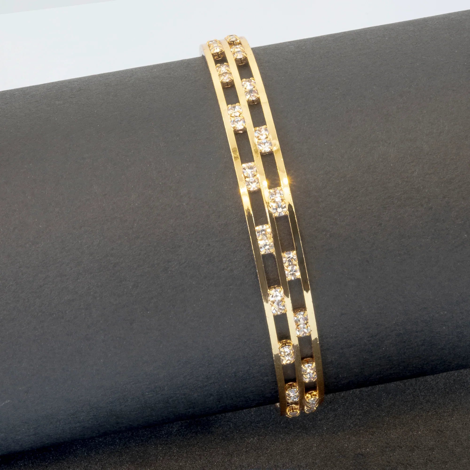 Gold bracelet with embedded diamonds on a dark surface
