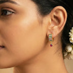 Close-up of a woman wearing a gold earring with gemstones.