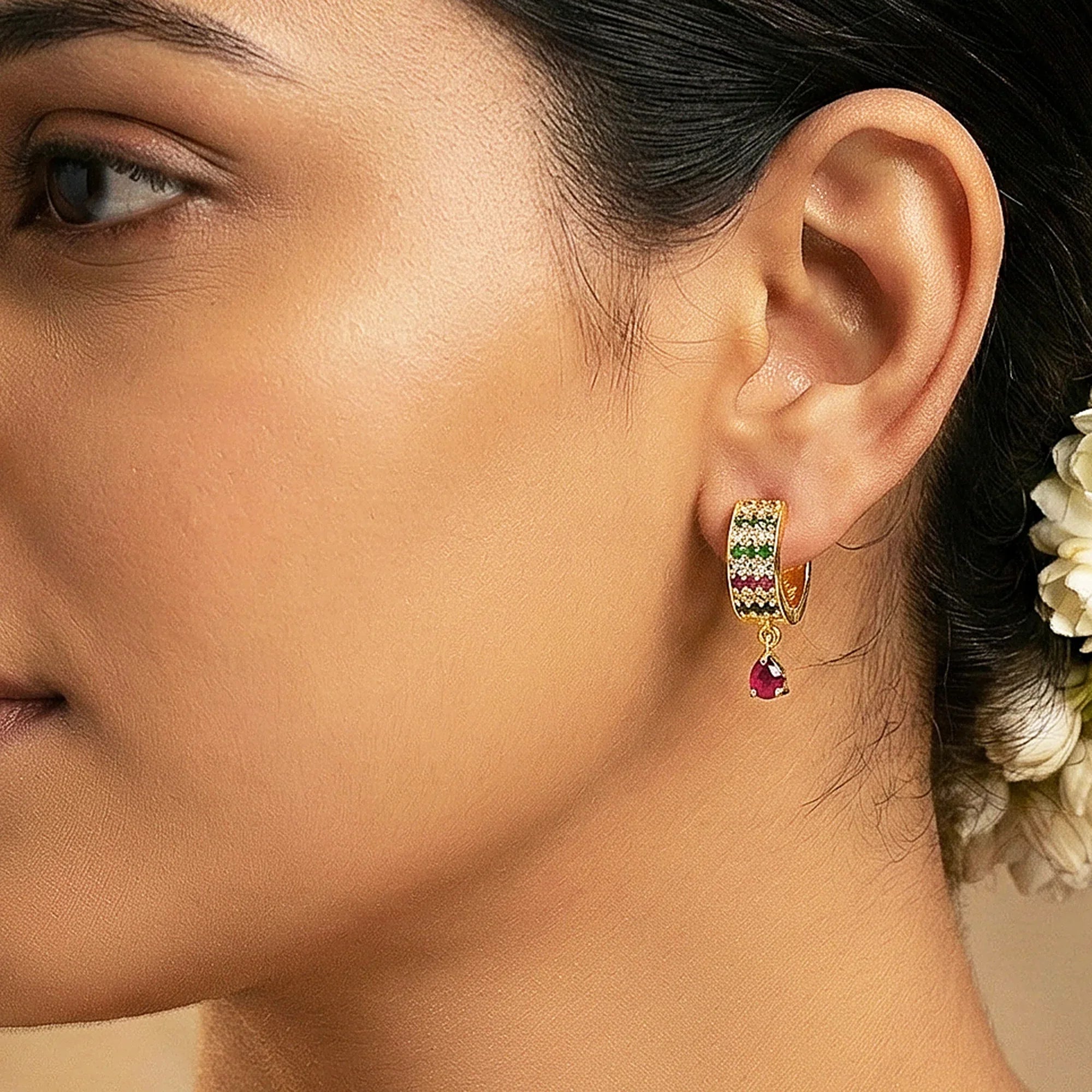 Close-up of a woman wearing a gold earring with gemstones.