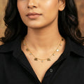 Woman wearing a gold necklace with elephant charms against a neutral background