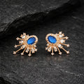 Pair of gold earrings with blue gemstones on a dark stone surface