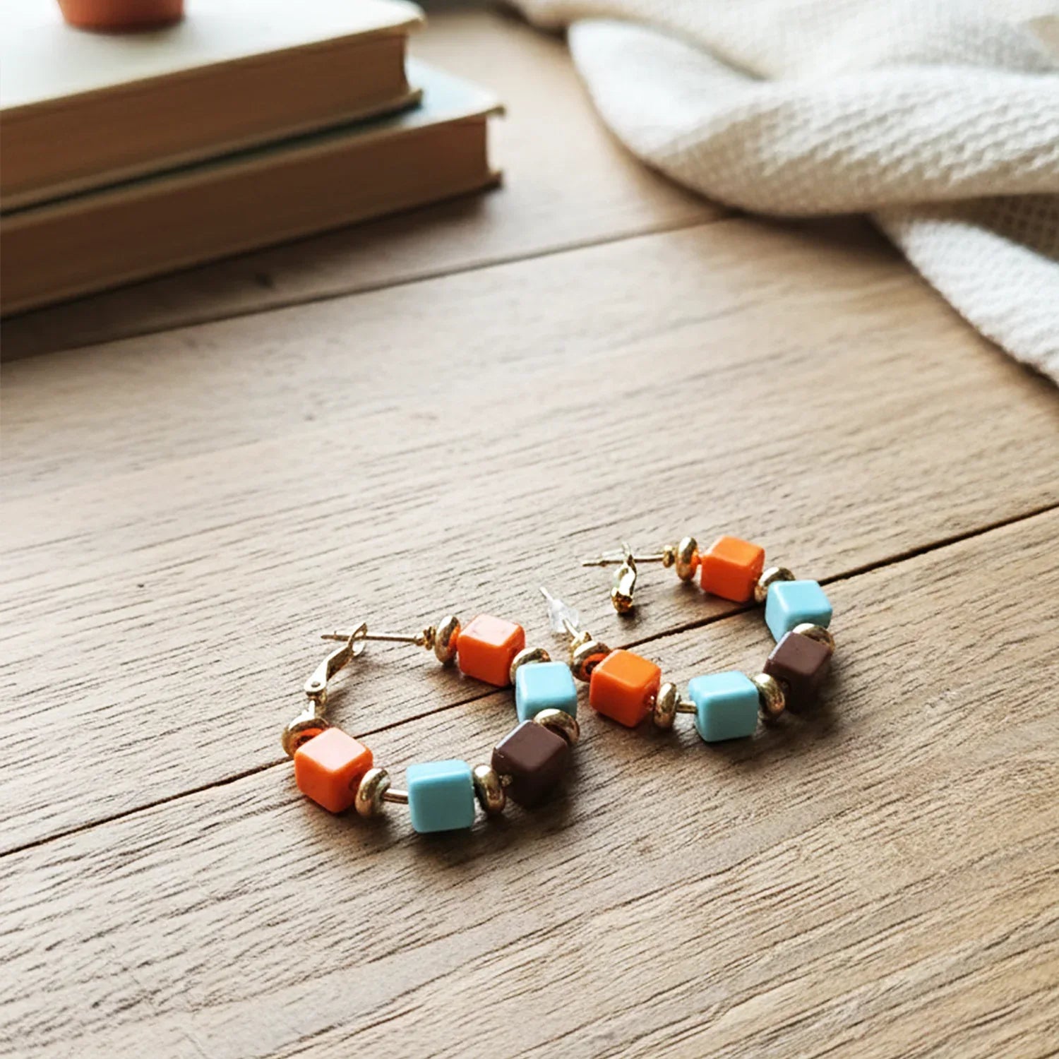 Colorful beaded bracelet on a wooden surface with books and a white cloth in the background