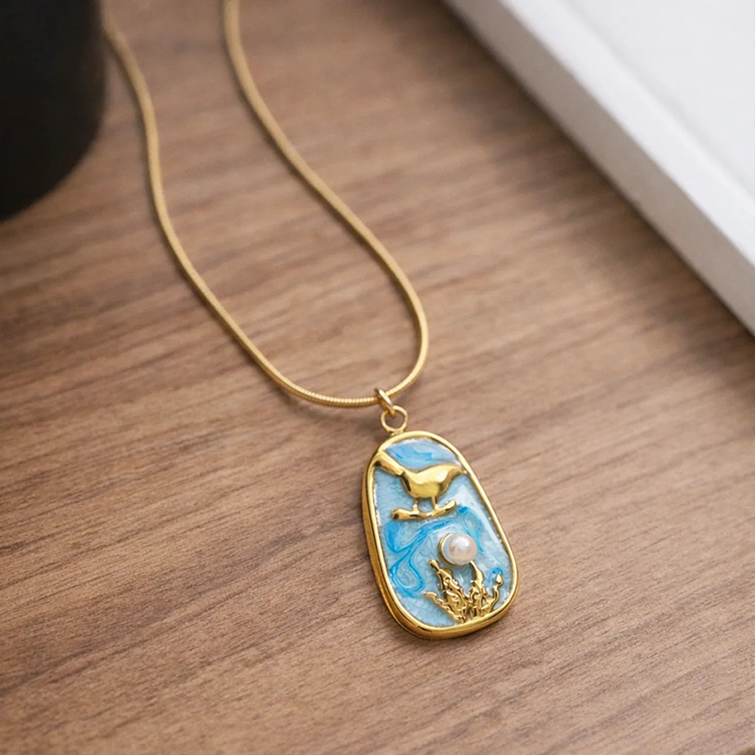Gold necklace with a decorative pendant on a wooden surface