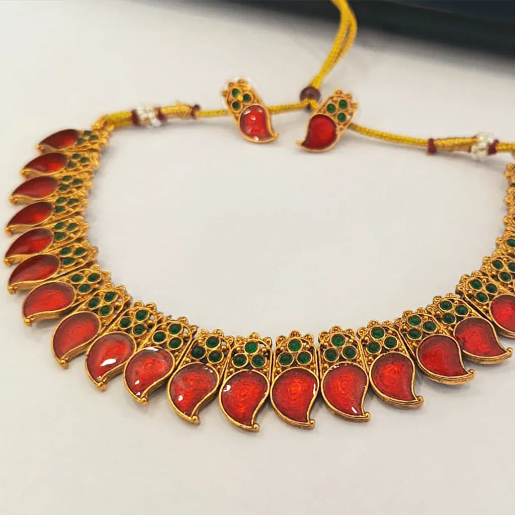 Ornate necklace with red and green stones on a white background
