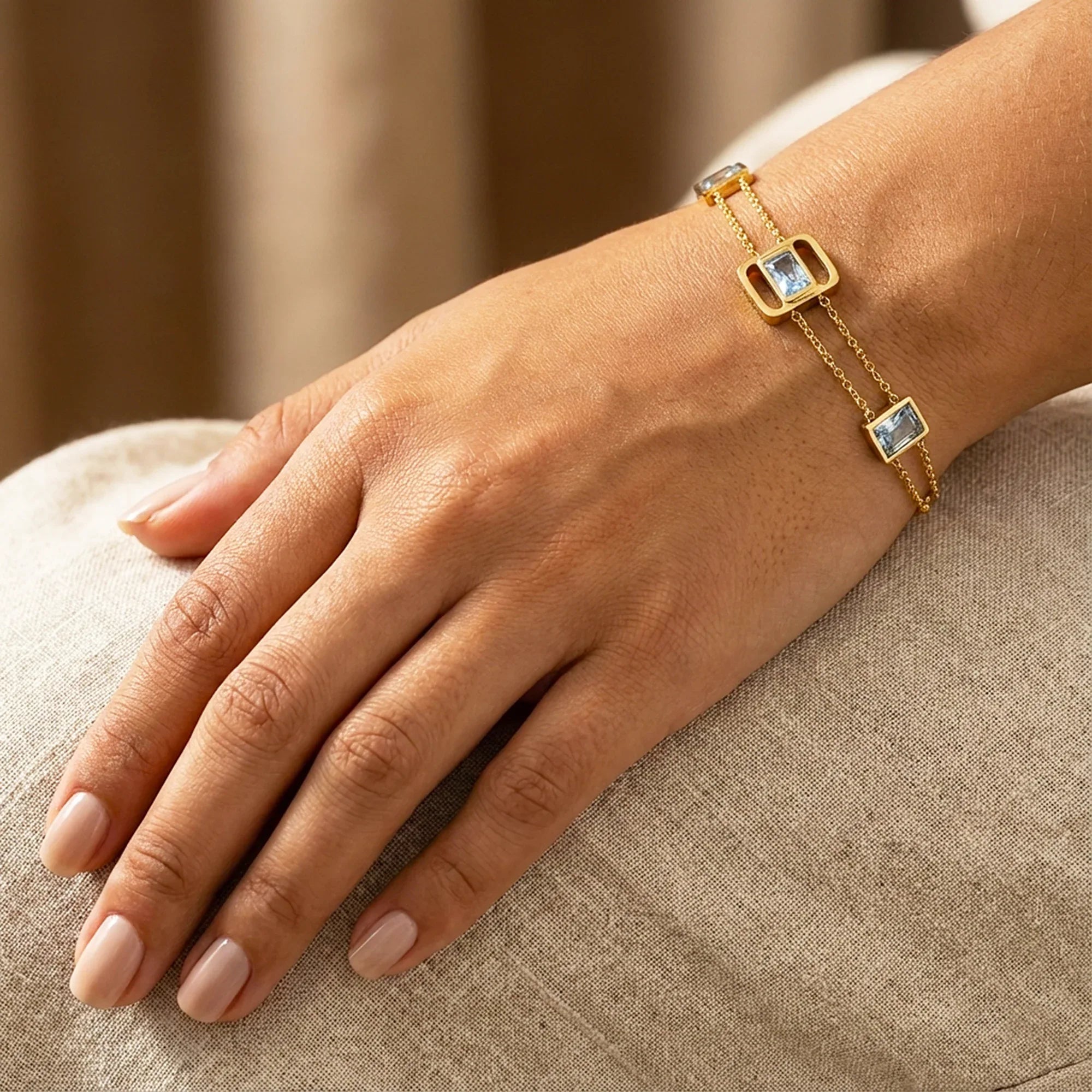 Gold bracelet with gemstones on a hand resting on a textured surface
