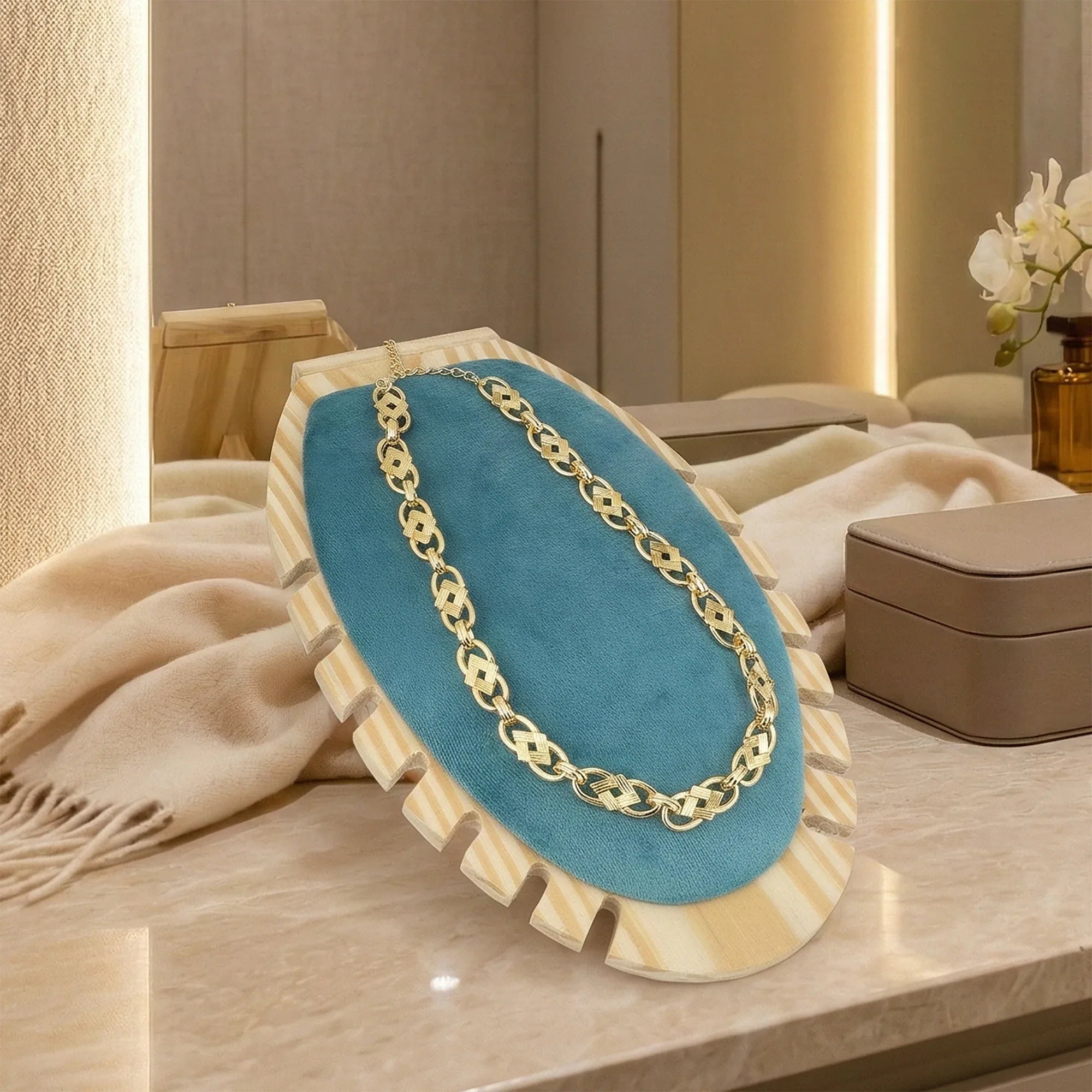 Gold chain necklace on a blue display stand with a neutral background