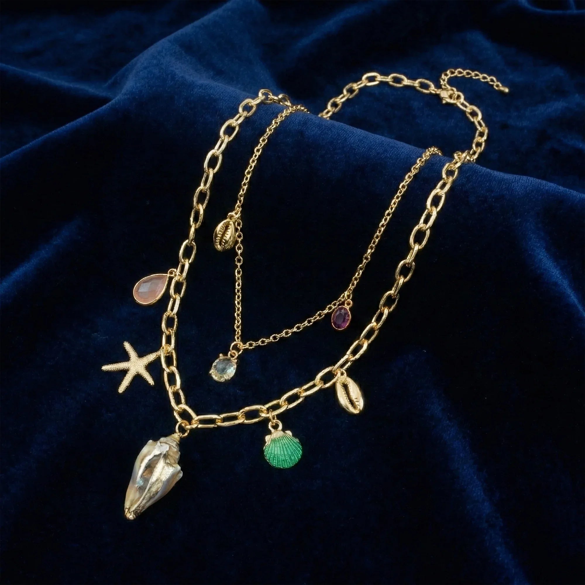 Gold necklace with charms on a dark blue fabric background
