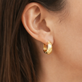 Gold hoop earring worn by a person with dark hair.