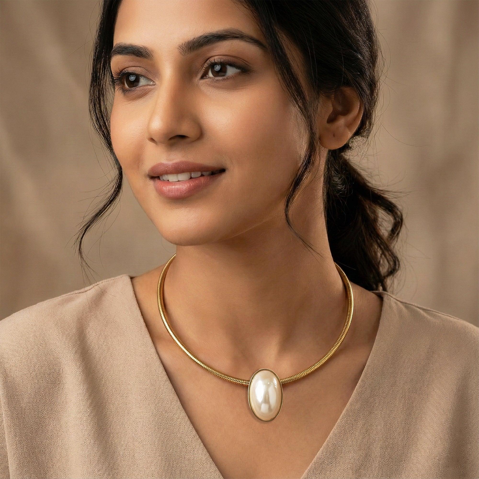 Woman wearing a gold necklace with a pearl pendant against a beige background