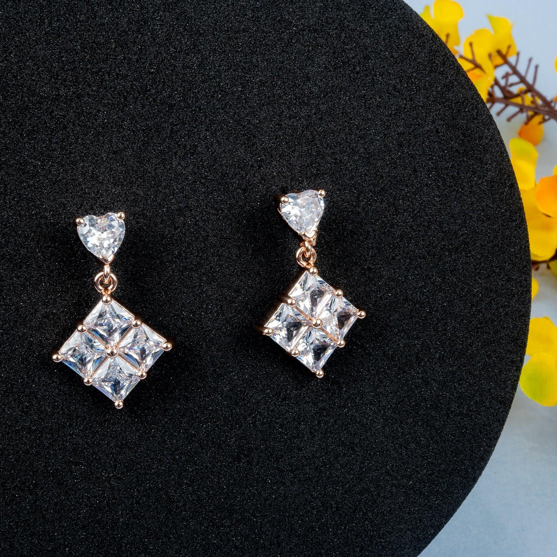 Pair of diamond earrings on a black stand with yellow flowers in the background