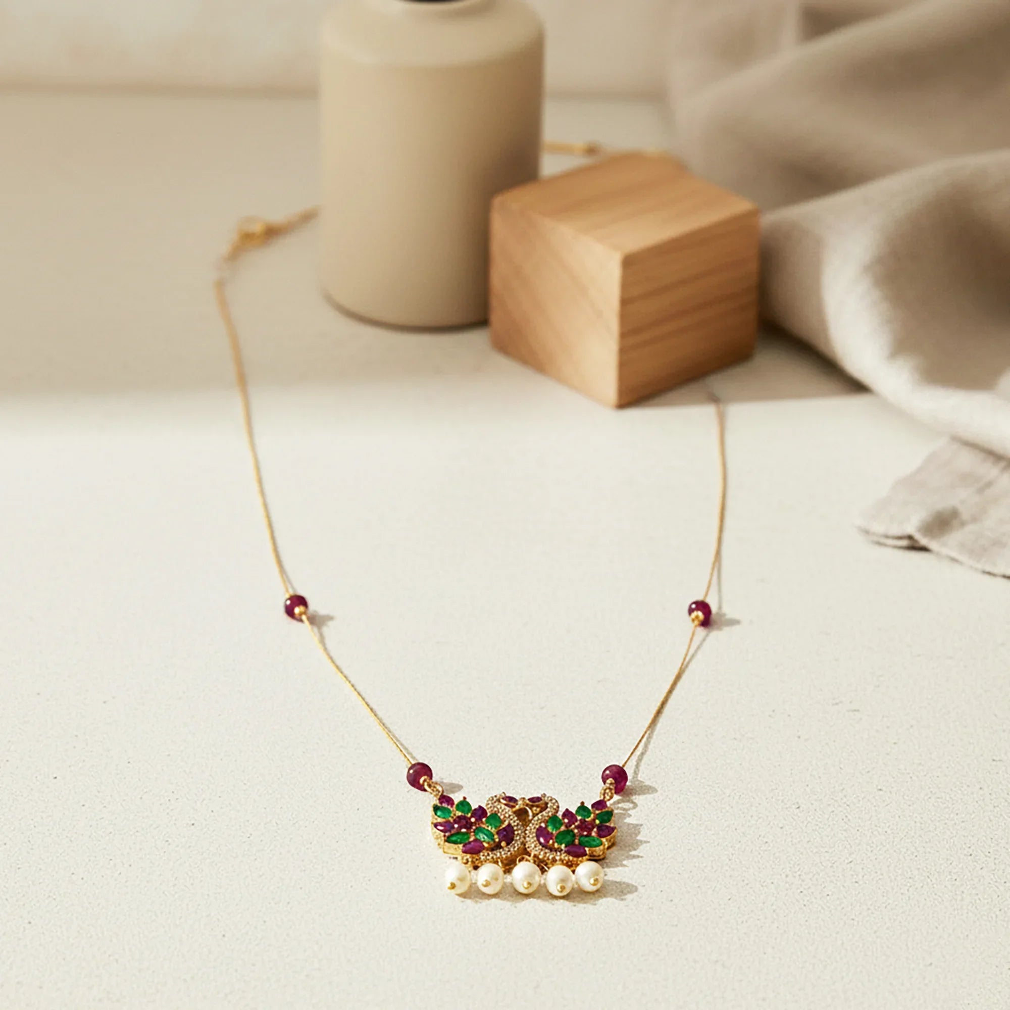 Gold necklace with gemstones and pearls on a light surface